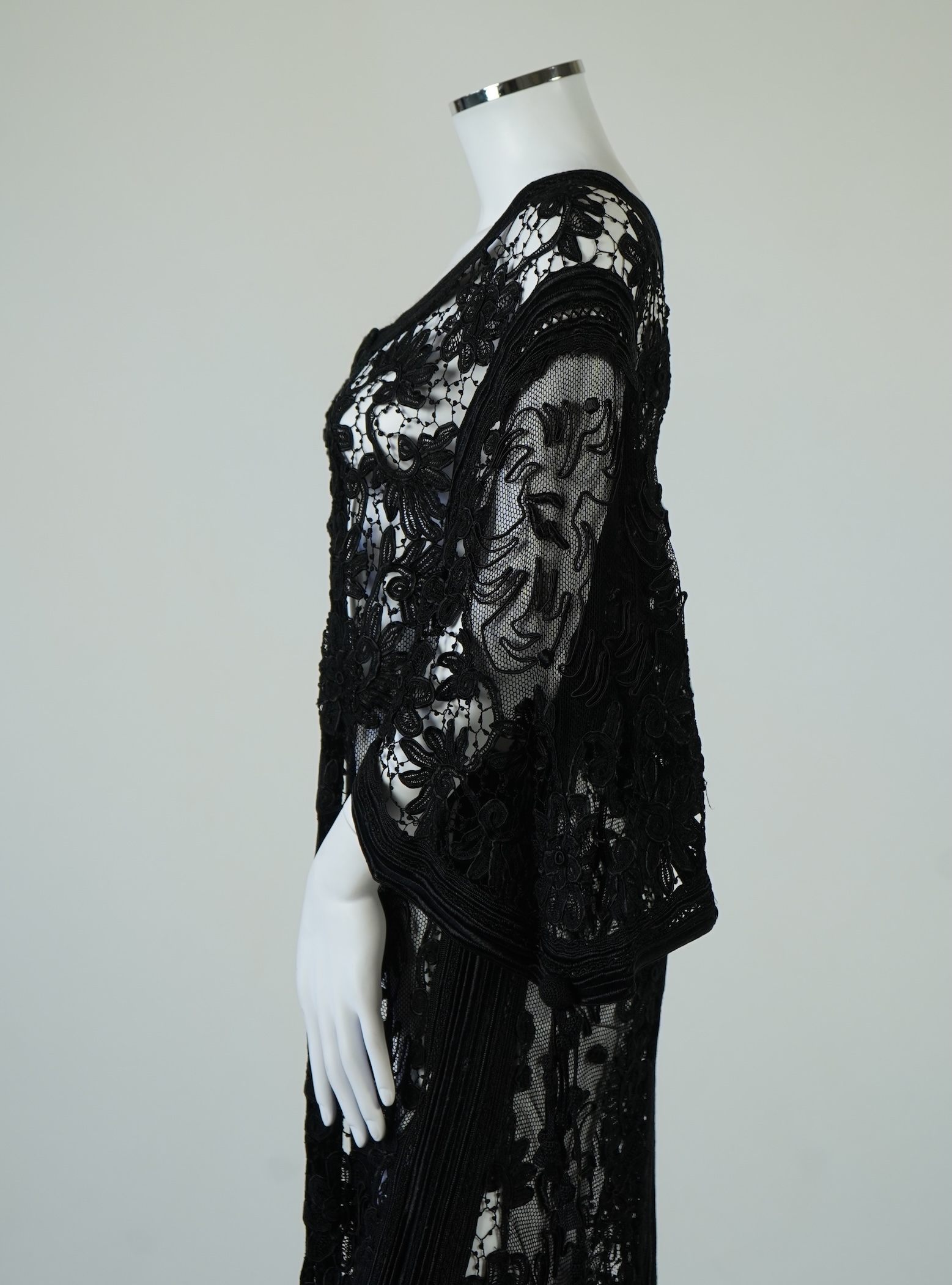 A late 19th century stylish ornate black silk tape lace evening coat/dress. Designed with a wide open neck, short bell sleeves with long tassels, four large buttons at the front and tails at the front and back. 130cm lon